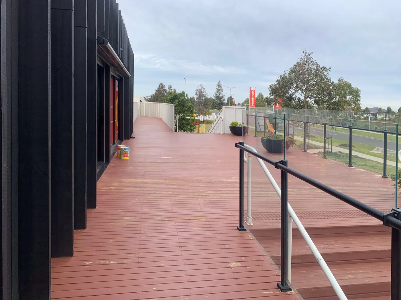 Walkway along the black facade before, red decking on a grey day, Point Cook