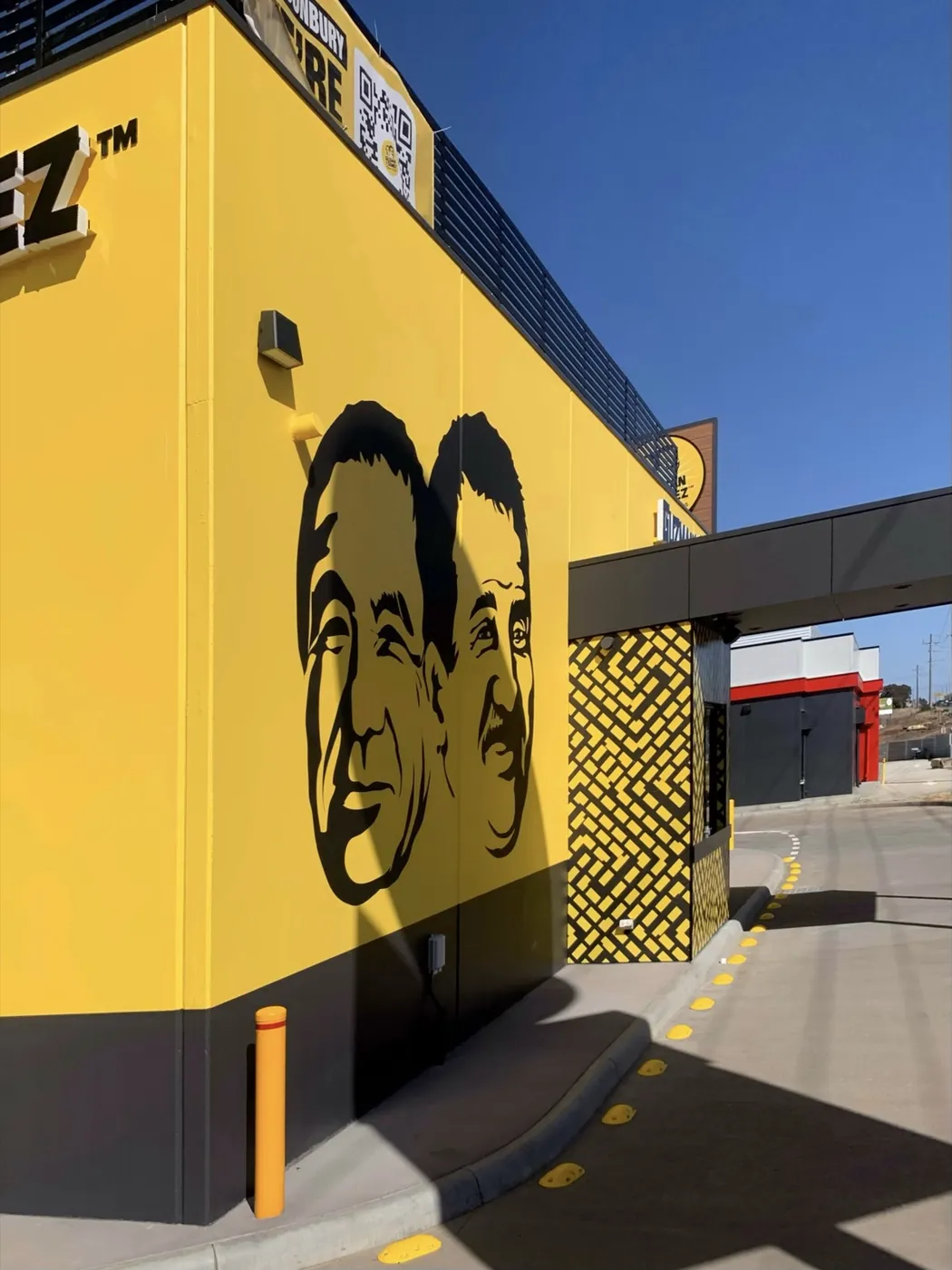 Guzman Y Gomez corner mural, bright yellow wall over a charcoal base, Sunbury