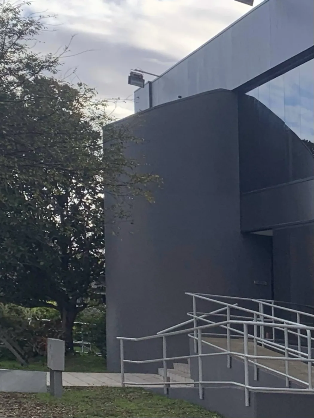 Same curved stair tower after, finished in an even charcoal above the white ramp, Footscray