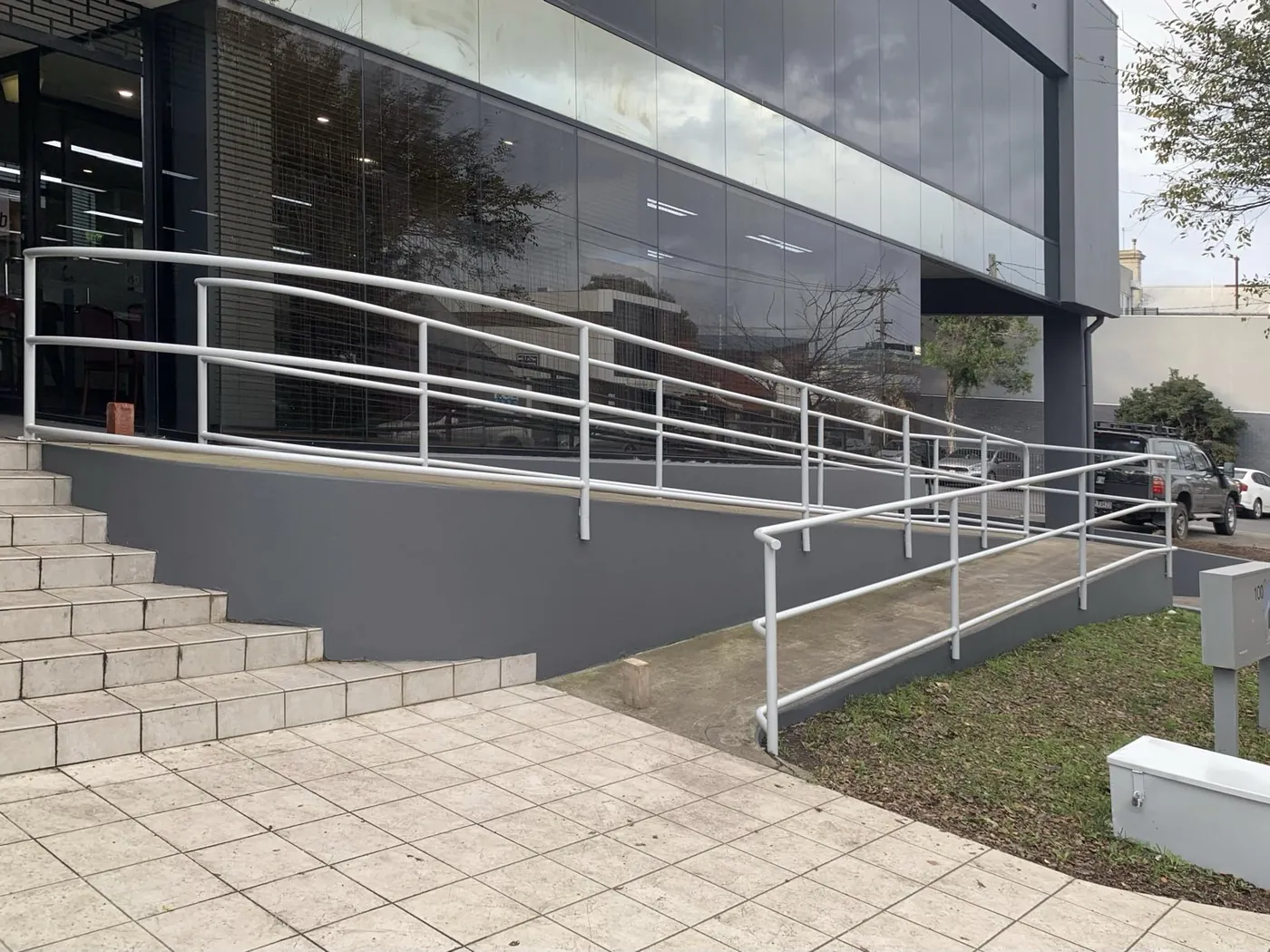 Same entrance after, walls repainted in deep charcoal with the white balustrades left clean, Footscray