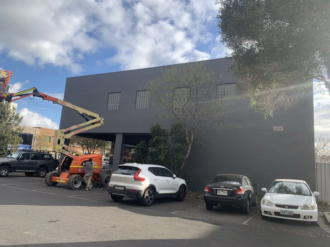 Same side elevation after, painted out in charcoal with a boom lift still on site, Footscray