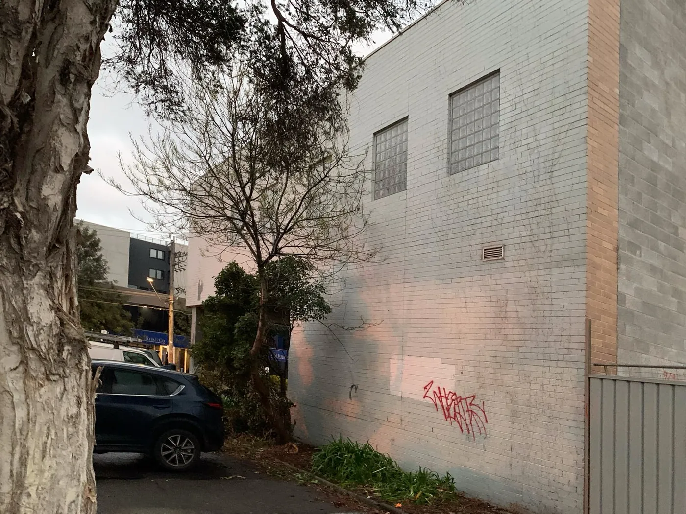 Side elevation before, pale painted brick marked with graffiti tags, Footscray
