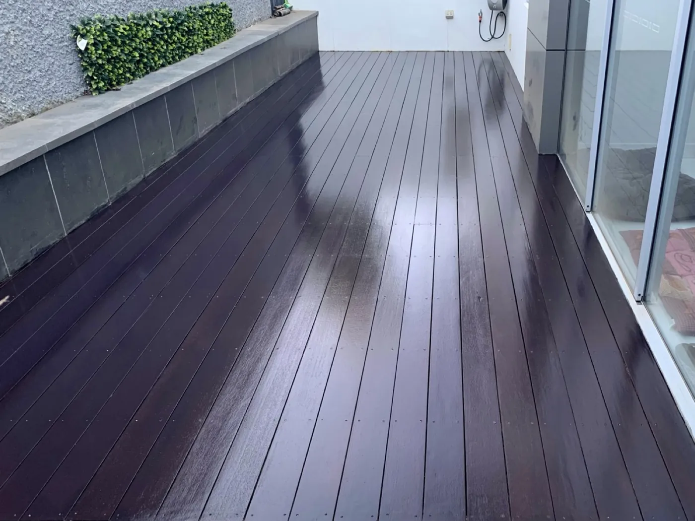 Timber deck coated in a deep tone alongside a glazed wall