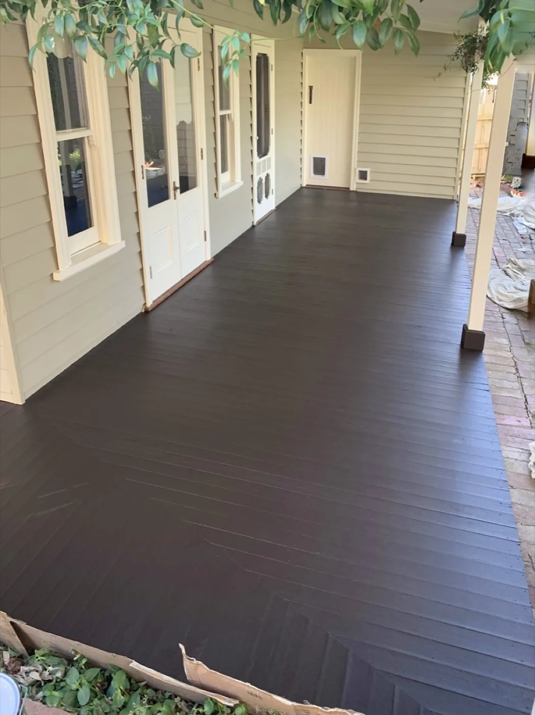 Verandah of a coastal home with the decking finished in a deep tone against pale cladding
