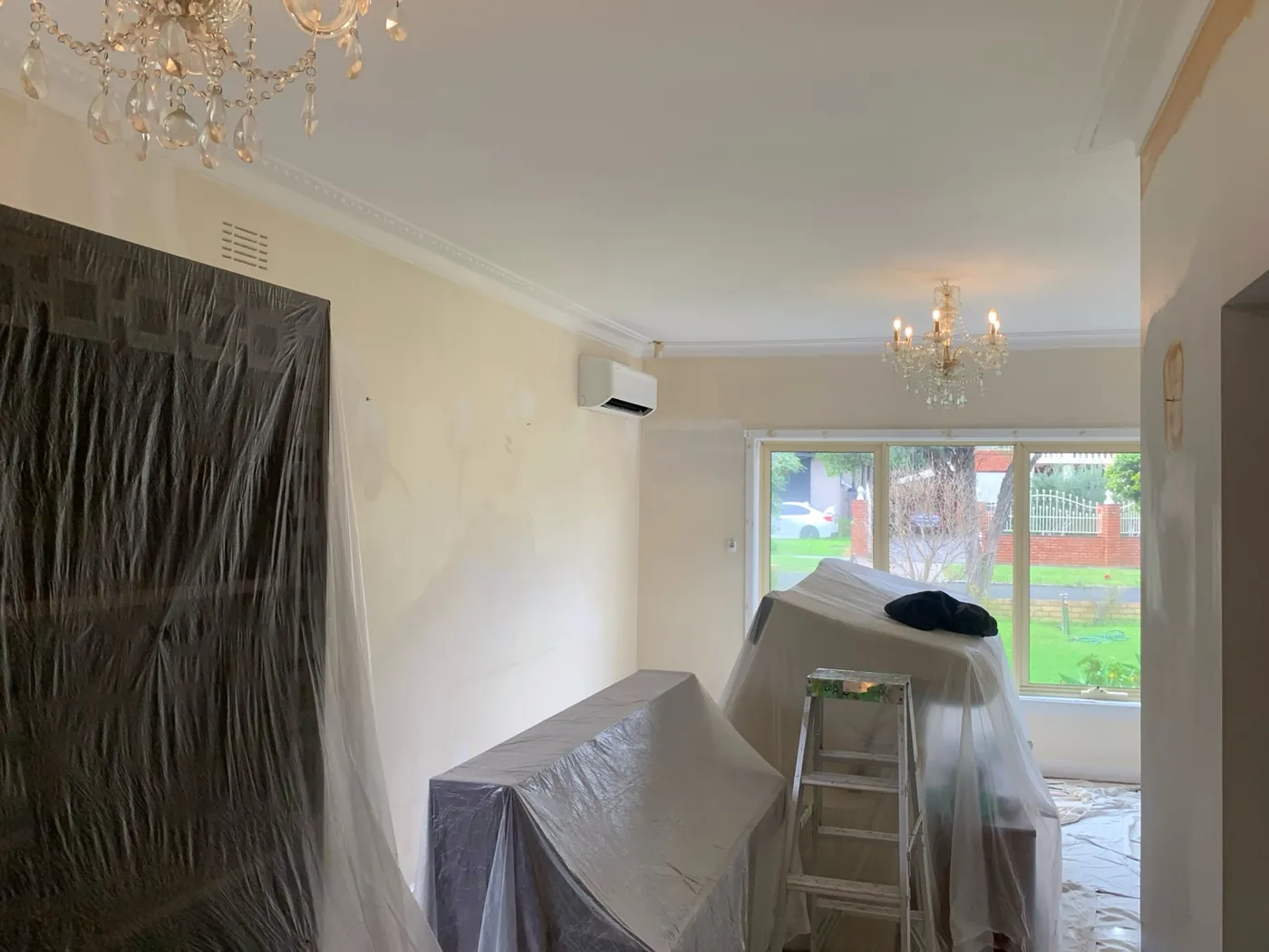 Living room part way through, built in cabinetry sheeted in plastic and furniture covered under the chandeliers, Oakleigh