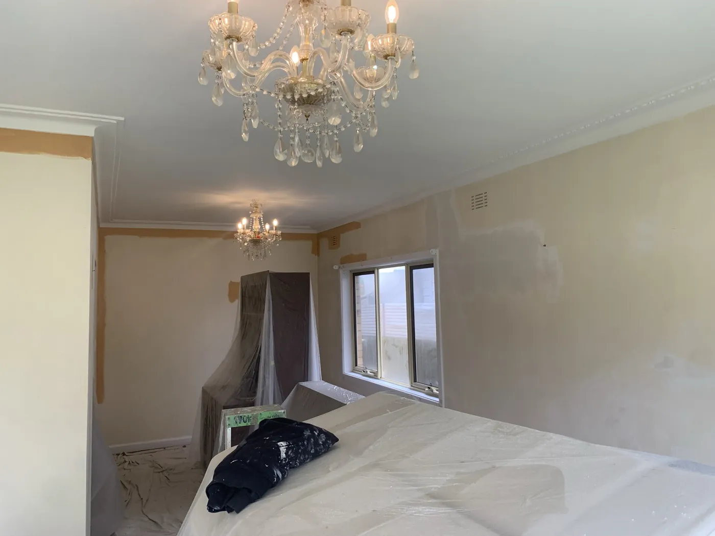 Bedroom part way through, the bed and wardrobe wrapped and the floor sheeted under the chandelier, Oakleigh