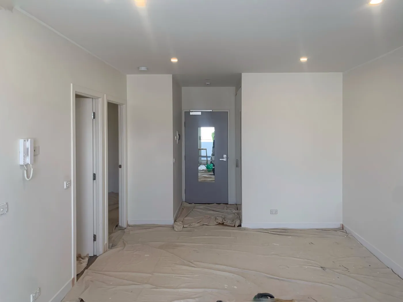 Apartment entry and living part way through, floors sheeted and the entry door still unpainted, Preston