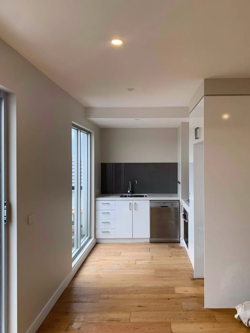 Same kitchen finished, warm greige walls beside the black splashback and clean oak floor, Preston