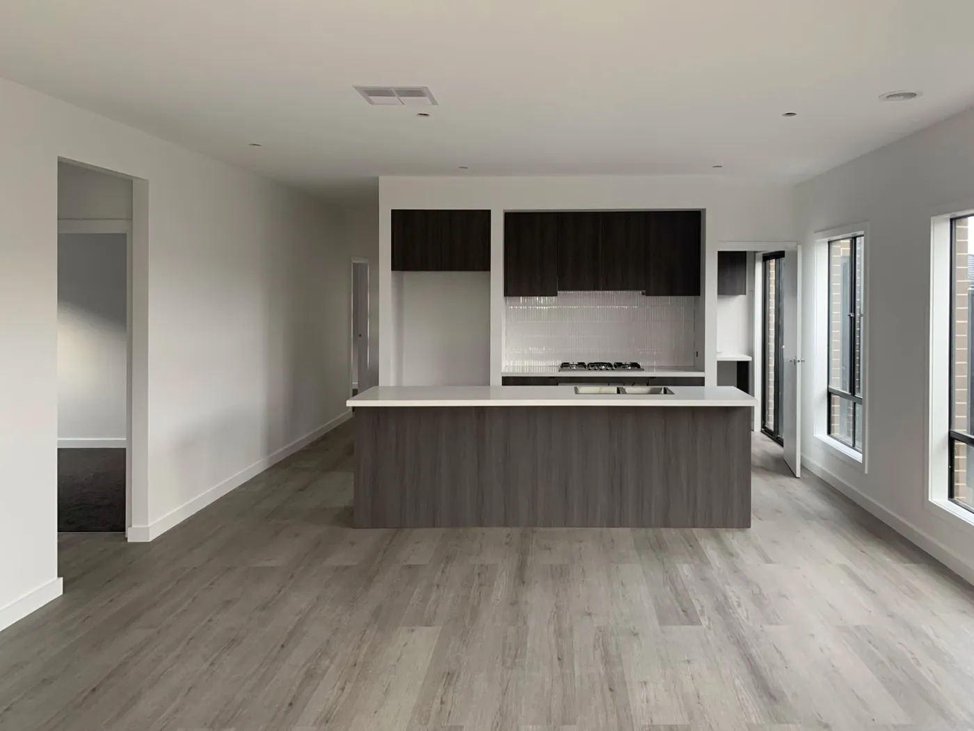 Open plan kitchen and living in a newer Melbourne home, painted throughout in a warm off white