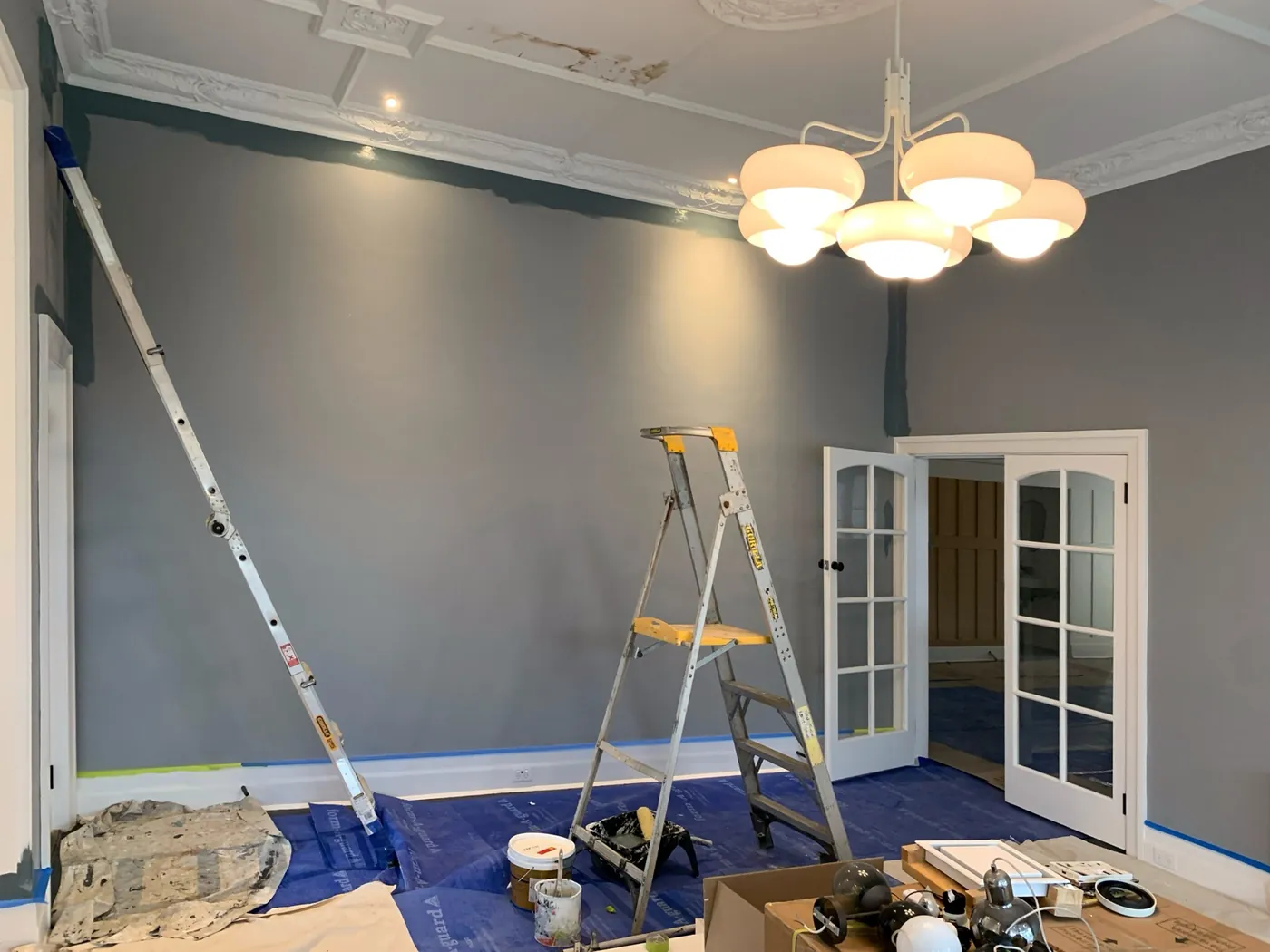 The same house during the work, ladder and drop sheets on a boarded floor with skirtings taped, Brighton
