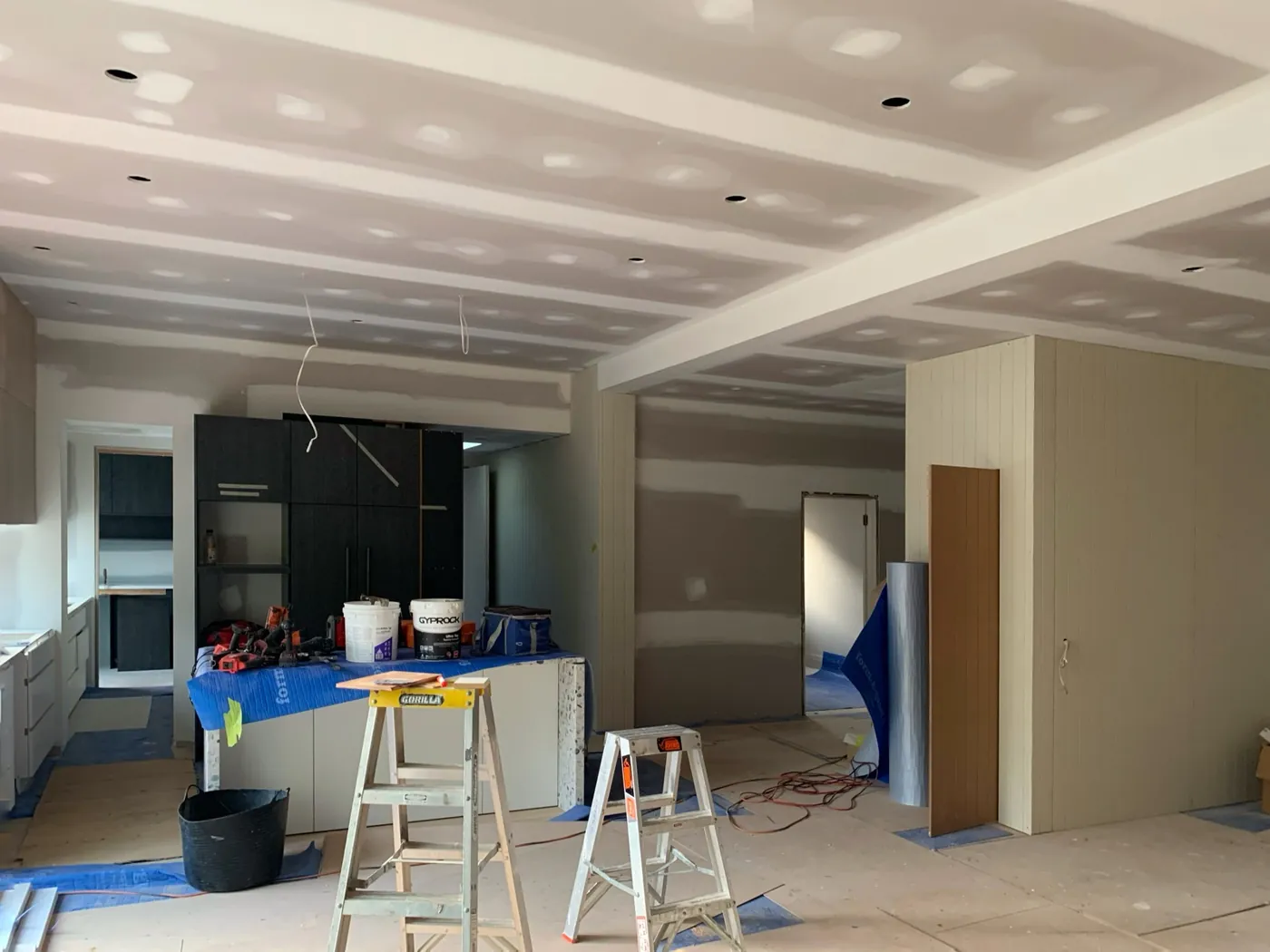 Open plan kitchen and living before, raw set plaster ceiling and walls with ladders and paint tins, Caulfield East