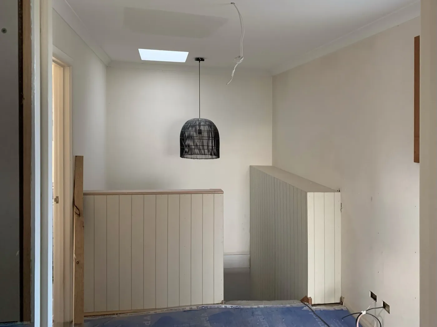 Upstairs landing before, bare VJ panelling and unpainted balustrade under a skylight, Caulfield East
