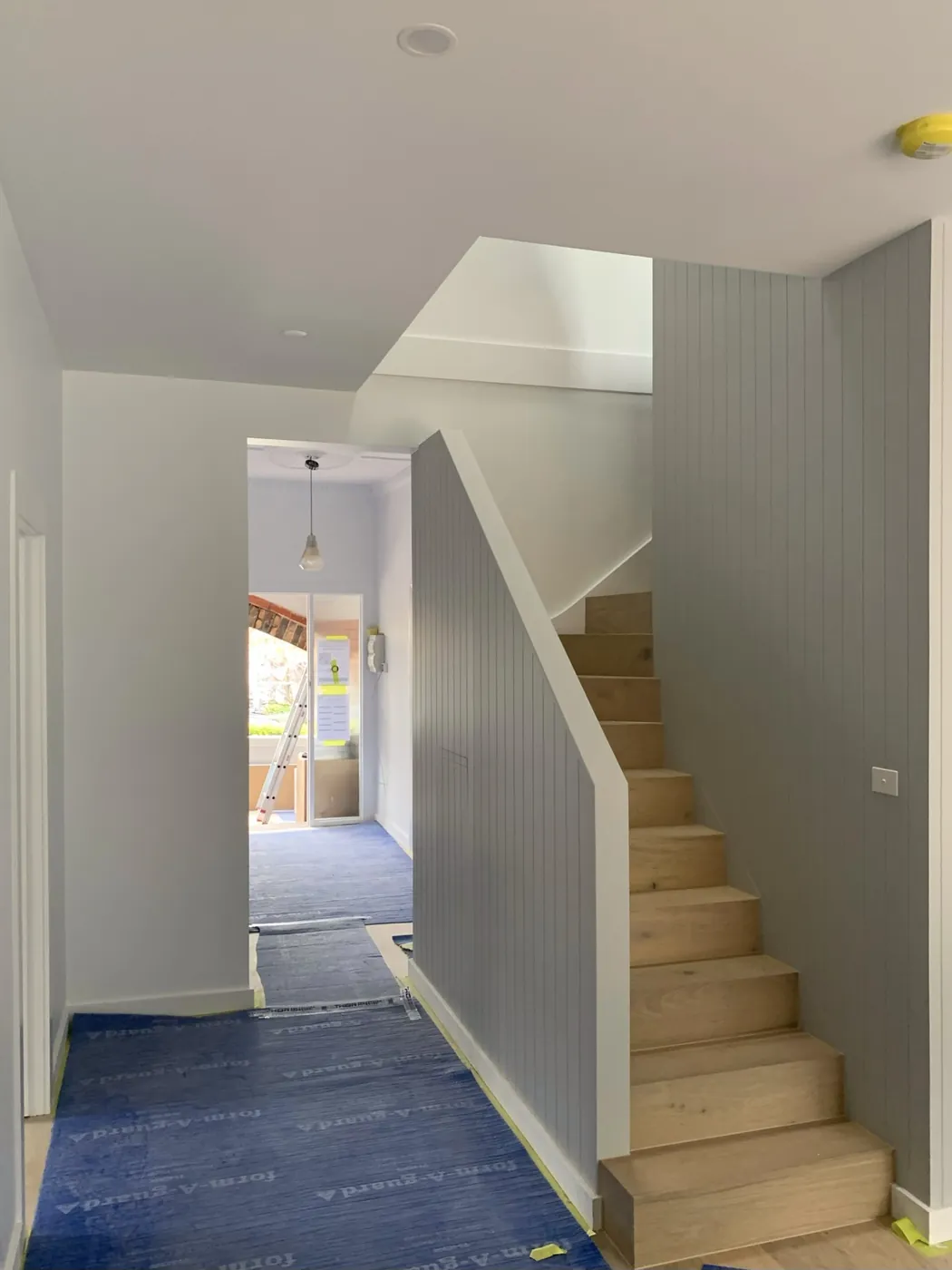 Timber staircase with the stair wall in soft grey VJ panelling and white trim, Caulfield East