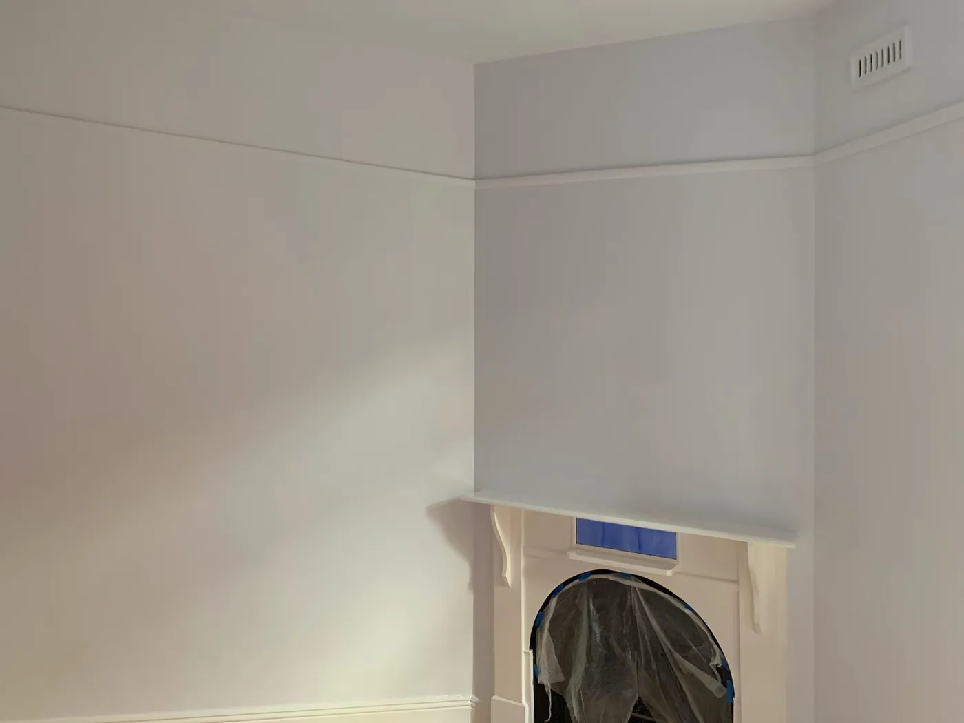 Finished corner of an old room, walls and cornice in an even off white with the fireplace masked off, Armadale