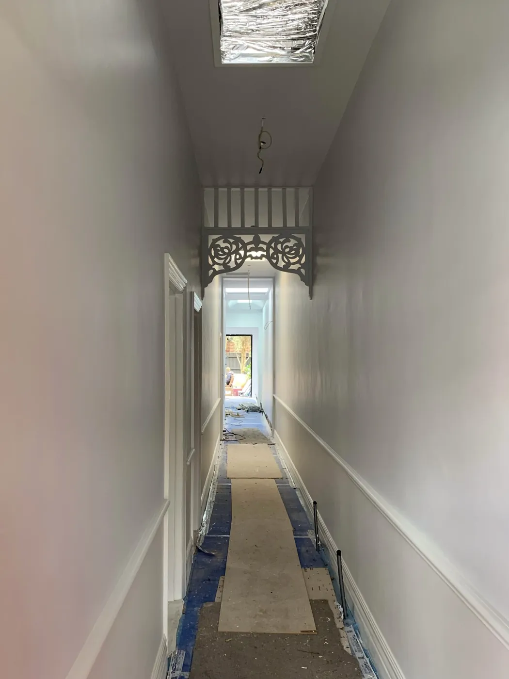 The same hall finished, arch fretwork and dado in crisp white down to the red front door, Armadale