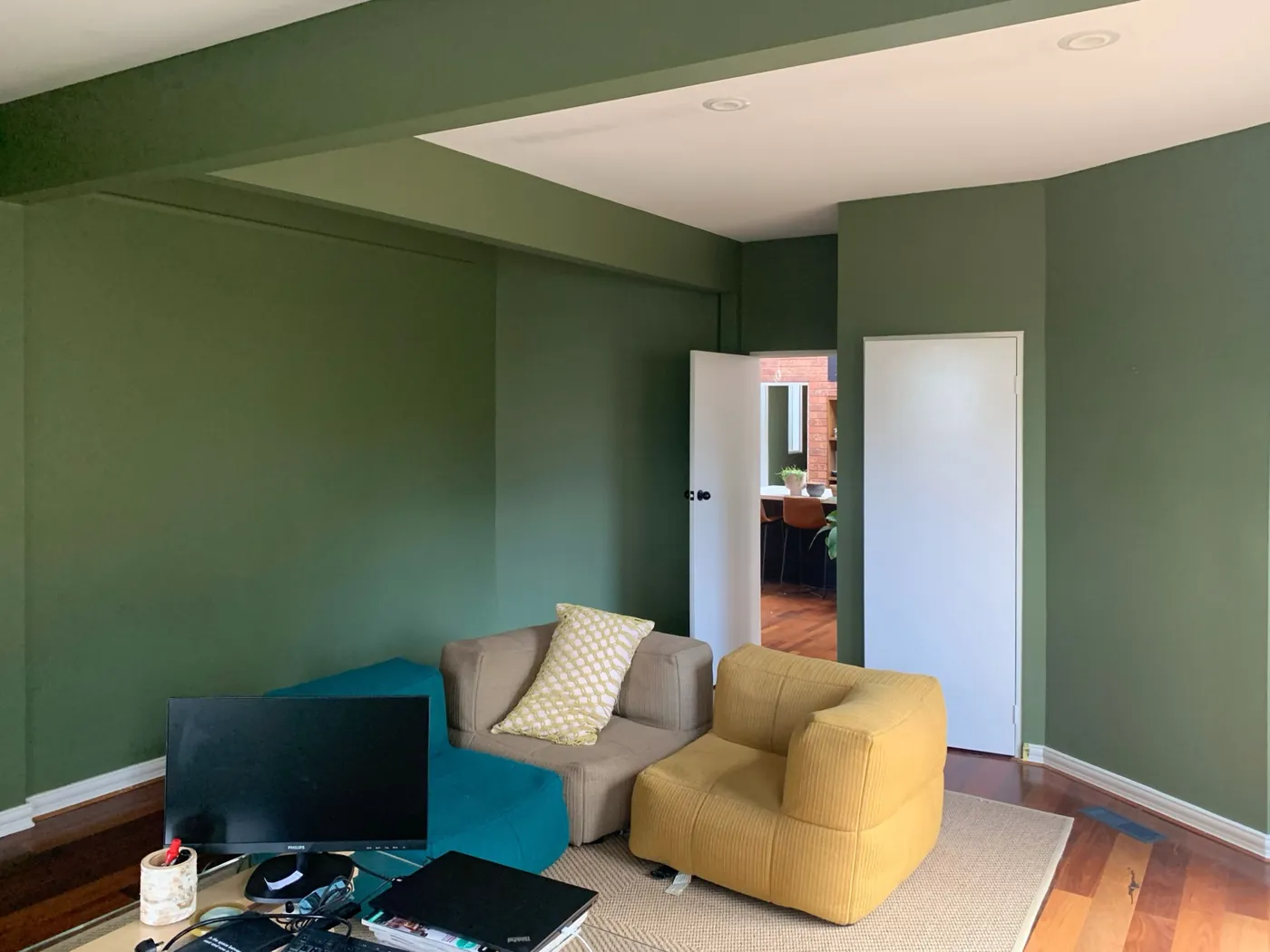 Living room in a bush setting painted in a deep olive with a white ceiling
