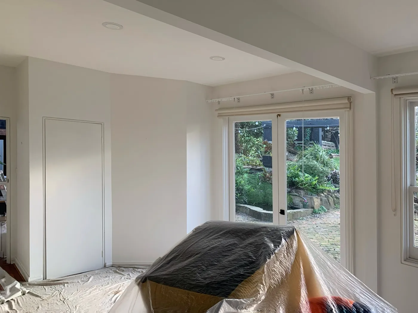 Living area before, white walls with furniture sheeted in plastic beside the garden doors, Ferntree Gully