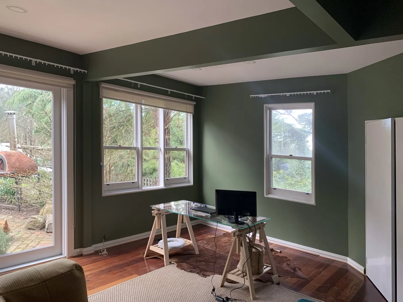 Study in deep olive with corner sash windows onto the trees and a white ceiling beam, Ferntree Gully