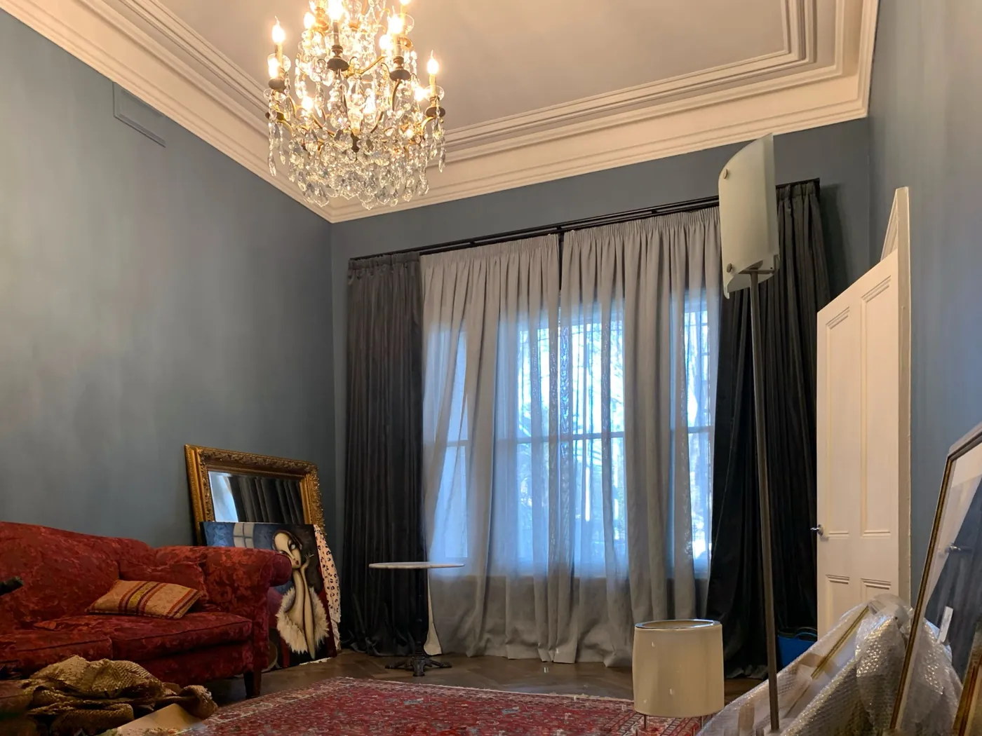 Large period lounge room repainted in a soft blue grey with white cornices and a chandelier