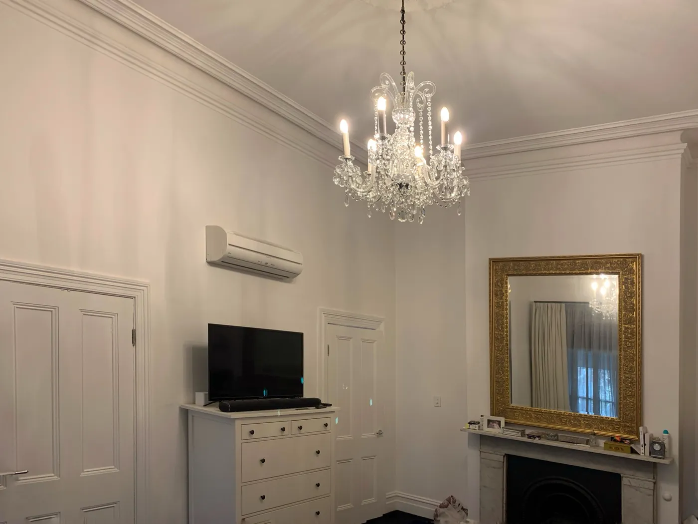 Victorian room with panelled dado and cornice in white, crystal chandelier and a gilt mirror over the fireplace, St Kilda