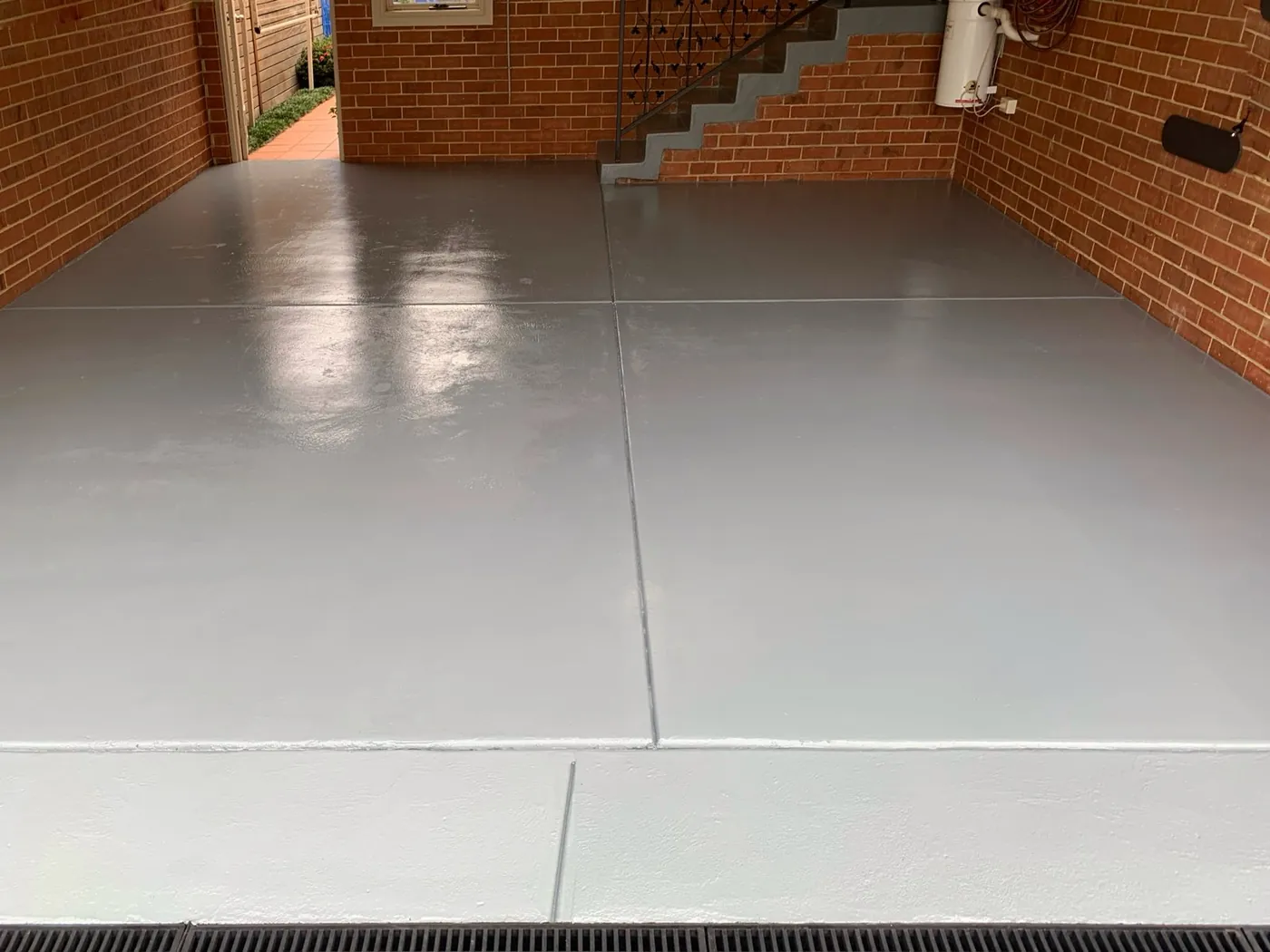 Finished garage floor close up, even grey coating running to the drainage grate, Balwyn North