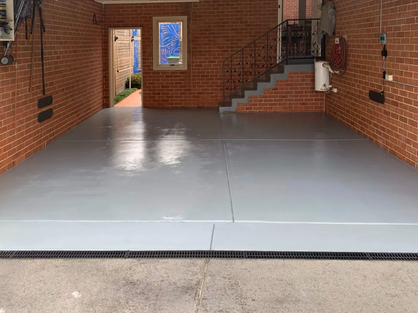 Same garage floor after, coated in an even mid grey with a clean edge at the door, Balwyn North