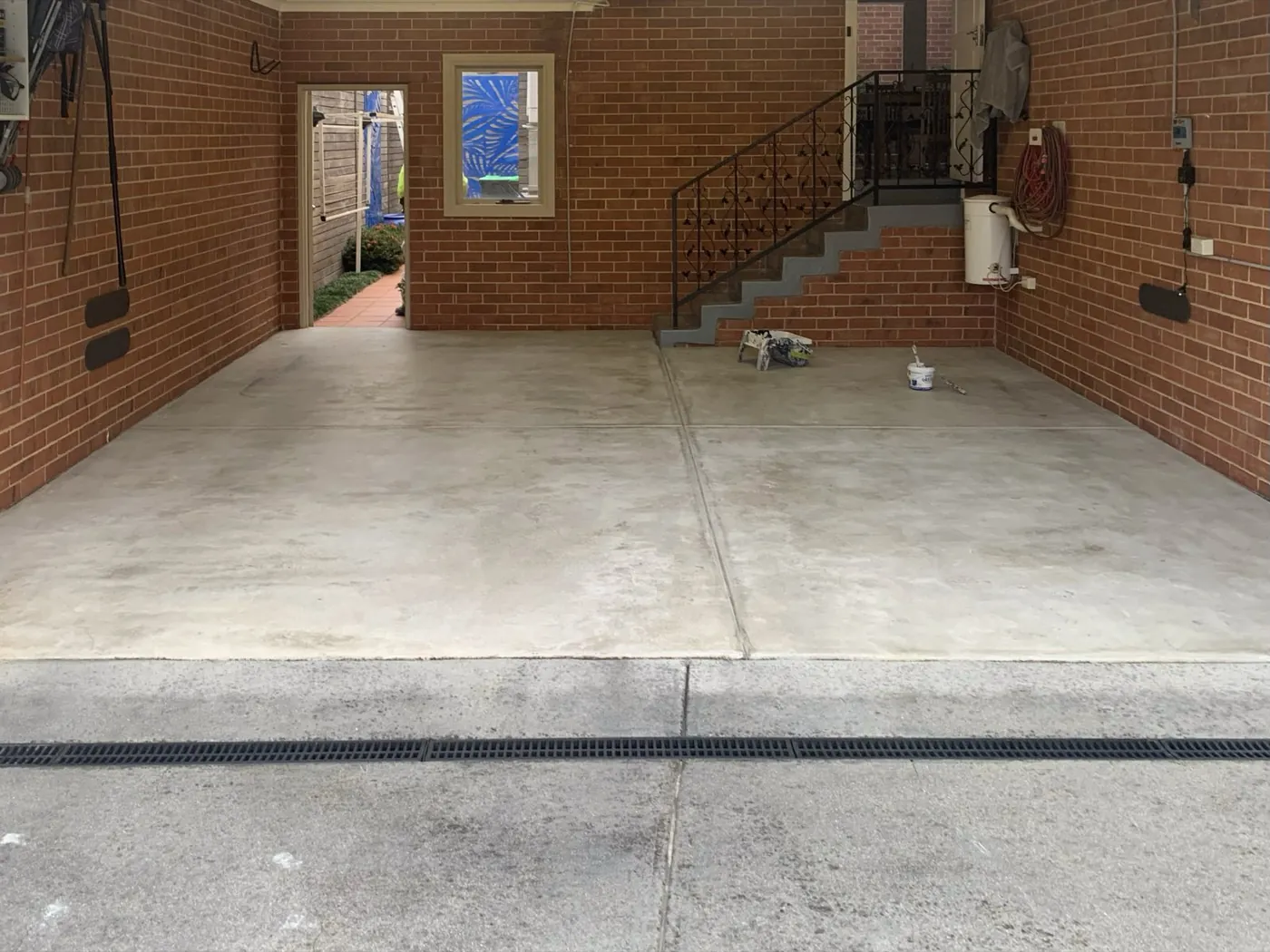 Garage floor before, stained and patchy concrete looking out to the driveway, Balwyn North